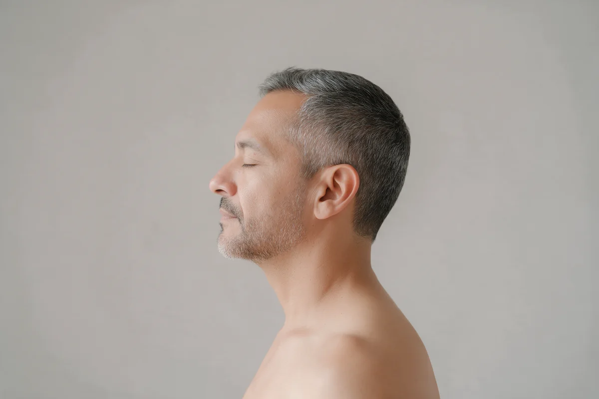 A man in profile with salt-and-pepper hair, eyes closed